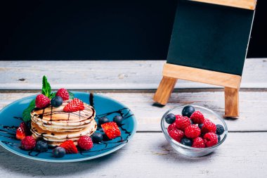 Çikolata şuruplu gözlemeler ve naneli taze meyve parçaları. Yabanmersini ve ahududu. Sağlıklı yemek. Boşluğu kopyala