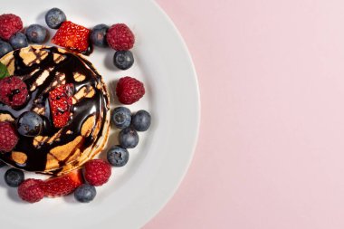 Meyveli krep ve pembe arka planda beyaz tabakta çikolata. Boşluğu kopyala