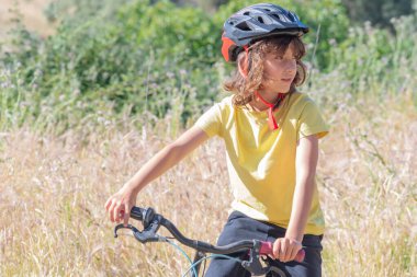 Kasklı küçük çocuk bisiklet sürerken eğleniyor ve gülümsüyor. Boş zaman ve boş zaman kavramı