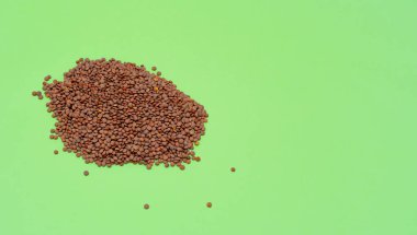 Bir sürü baklagil, yeşil arka planda çiğ mercimek. Yemek pişirme, yemek ve sağlıklı yaşam tarzı kavramı. Yırtıcı bir madde ve demiri vardır. Boşluğu kopyala