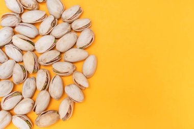 Turuncu arka planda fıstık yığını. Fındık lifinin kaynağı. Bakım, yemek ve sağlıklı yaşam tarzı kavramı. Boşluğu kopyala