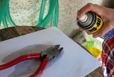 Atina, Yunanistan-30 Ekim 2020. Bir kişi kerpetene WD-40 delici yağ püskürtüyor.