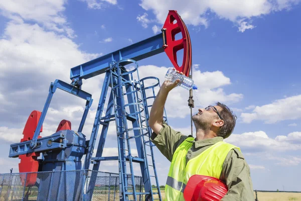 Arbetstagaren uppfriskande efter hårt arbete på oljepumpen. — Stockfoto