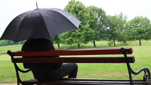 Bei Regen auf Bank sitzen und gehen. — Stockvideo