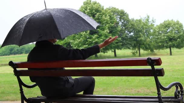 Sentarse en el banco y comprobar con la mano si llueve . — Vídeos de Stock