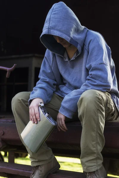 Homem sem-teto sentado e segurando um frasco — Fotografia de Stock