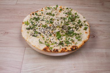 Tandır kulcha ya da naan olarak da bilinen Hint özel düz ekmeği, beyaz seramik çeyrek tabakta servis edilir.