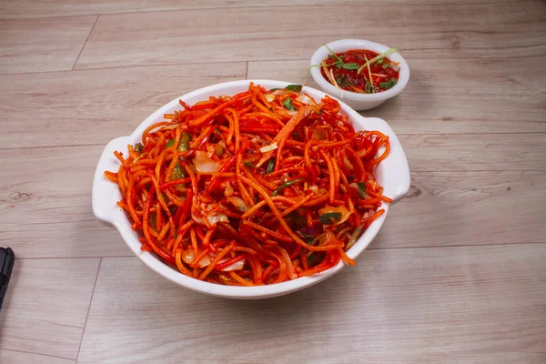 Schezwan Veg Noodles is a popular Indo-Chinese dish that is prepared with noodles, vegetables and show sauce and is served on a rustic wooden background, selective focus