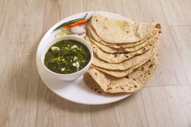 Ispanak ve süzme peynirden yapılmış Palak Paneer Curry, Popüler Hint Sağlıklı Öğle Yemeği / Akşam Yemeği menüsü, ahşap arka planda Roti veya Chapati ile servis edilen bir kasede. seçici odak