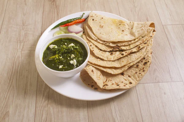 Ispanak ve süzme peynirden yapılmış Palak Paneer Curry, Popüler Hint Sağlıklı Öğle Yemeği / Akşam Yemeği menüsü, ahşap arka planda Roti veya Chapati ile servis edilen bir kasede. seçici odak