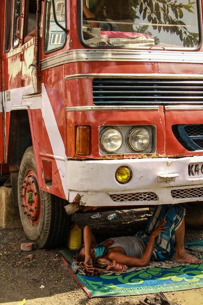 Bir kamyon şoförü Corona sırasında bir kamyonun altında dinleniyor..