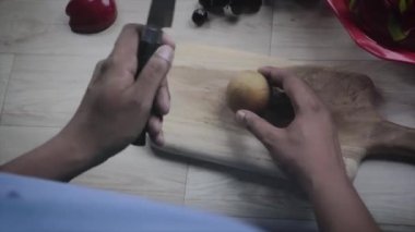 Bıçakla sapodilla kesmek. Şef sapodillayı kesme tahtasıyla keser. Sağlıklı gıda konsepti. Bir adam sapodillayı ikiye böler. Doğal bulanıklık ve sallanan kamera..