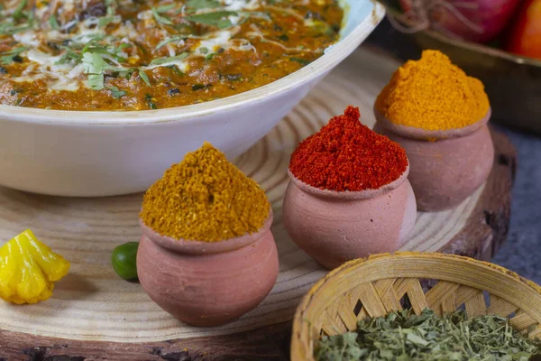 Indian Colourful Spices Also Know as Red Chilli Powder, Turmeric Powder, Coriander Powder, Mirchi, Mirch, Haldi, Dhaniya Powder Isolated on wooden Background in pitcher.selective focus.