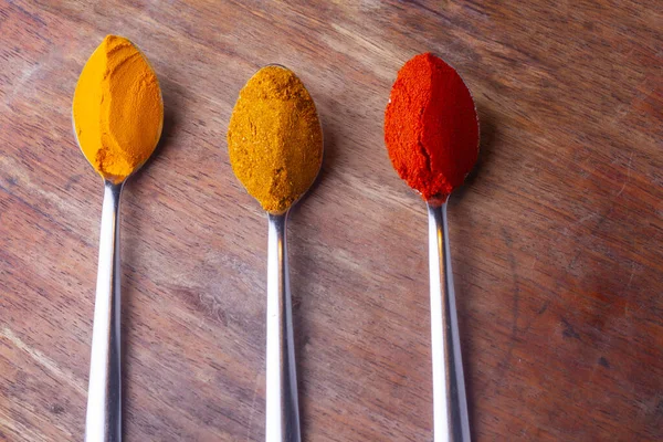 Indian Colourful Spices Also Know as Red Chilli Powder, Turmeric Powder, Coriander Powder, Mirchi, Mirch, Haldi, Dhaniya Powder Isolated on wooden Background in spoon.