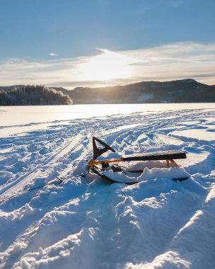 Kar yarışçısı, kar kızağı ya da direksiyon simidi ve frenle kaplı bir gölde ormanla çevrili bir kızak. Mavi gökyüzü ve güneş ışığıyla beyaz karlı arka plan