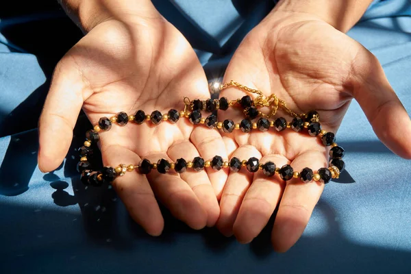 Siyah renkli dua boncuğu avucunun içinde, gölgeli.