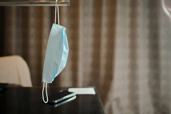 Blue surgical face mask hanging at the hotel room desk