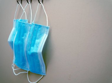 Gri arka planda asılı mavi cerrahi maske