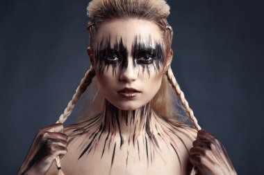 Kadının yüzüne ve vücuduna boya çiziyor.