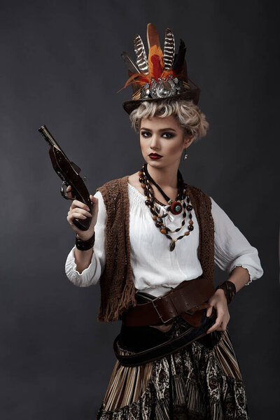 Beautiful girl in steampunk style costume with hat and handgun