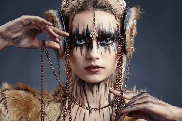 Kadının yüzüne ve vücuduna boya çiziyor. Yüksek moda tarzı