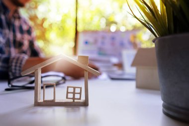 Ev kredisi ve emlak işi kavramı. Gayrimenkul acentesinin geçmişi konut fiyatlarını hesaplamak için çalışıyor, model ev teklif ediyor, ev satın alma sözleşmesini imzalıyor.