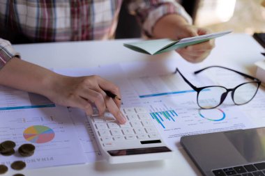 Genç girişimci ya da iş adamı el ele tutuşup hesap defteri tutuyor ve hesap makinesi kullanıyor. Giderler, hesaplar, vergiler, ev bütçesi kavramı.