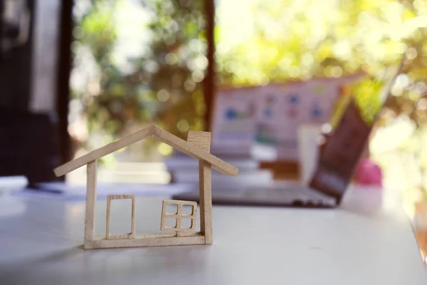 Arka planı olan küçük ahşap model ev emlakçı konutun fiyatını hesaplar. Ev almak ve satmak ve emlak fiyatları kavramı.