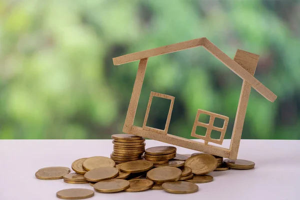 Minyatür ahşap ev modeli, yığınla para ve arka plan ekonomisi. Home Eco ve Emlak kavramı.