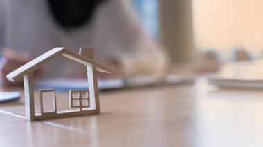 Emlakçılı ahşap manken evi ya da banka ofisi ev kredisi, satış konutları, ev satın alma sözleşmeleri üzerinde çalışıyor. Sancak arkaplanı ve kopyalama alanı.