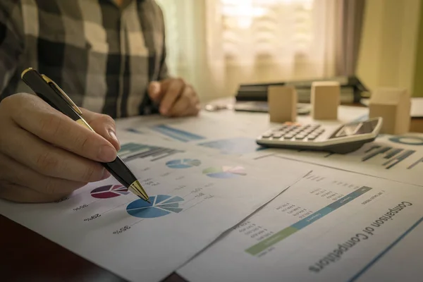 Analyst Brokers or Businessman are analyzing statistical charts on real estate share, the housing market, business property income on table with a calculator, model, document.