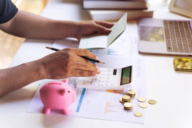 İş adamı ya da girişimcinin elinde hesap defteri, hesap makinesi, bozuk para, istatistiksel kazanç ve gelir raporu var. Hesap kavramı ve kaydetme.