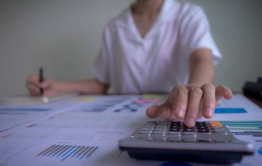 Kapatın, işkadını eli hesap makinesi ve yazı makinesi kullanarak maliyet, vergi ve mali konuları ile ilgili not alın..