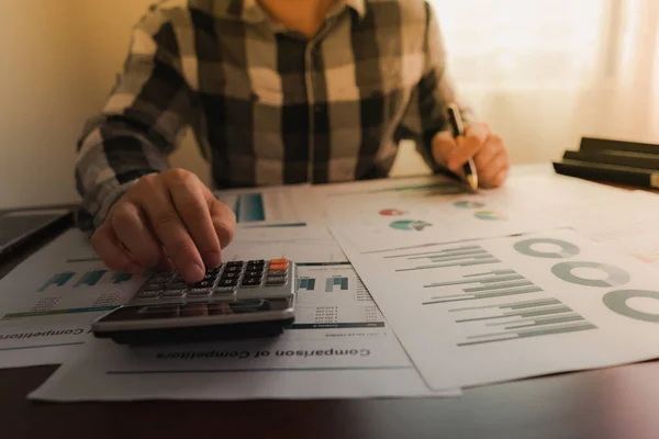 İş adamı, iş yerinde hesap makinesi ve istatistik istatistikleri kullanarak gelir elde ediyor.