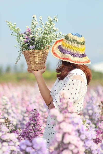 A woman in a vintage dress holds a flower basket in a beautiful flower garden to collect flowers and admire the beauty of the expanses alone.The concept of loneliness of a young woman