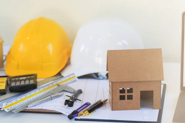 Model ev, mühendislerin ve tasarımcıların masalarının üzerinde yatırımcıları tasarımlarıyla memnun etmek için durur. Emlak yatırımcısını memnun etmek için mimarların ev tasarımı fikirleri.