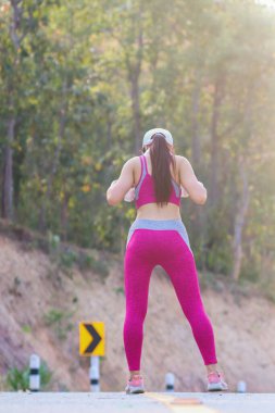 Bulanık görüntü, spor kıyafetleri içinde, ayakta duran genç bir kadın, sabah koşabilmek için bacağını ve ayak kaslarını gevşetmek için ısınıyor. Koşu meraklılarının yarışa hazırlanma konsepti.