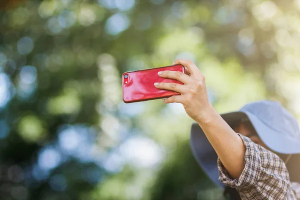 A young female tourist is using a selfie to take a selfie with a beautiful view to share on Social Media. The idea of taking a selfie if you are in a tourist destination to share on Social Media.