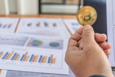 Genç bir işadamı Bitcoin 'i elinde tutuyor çünkü sanal paraya ya da kripto para birimlerine yatırım yapmaya inanıyor. Şifreleme parasının sembolü olan bir altın sikke.