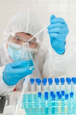 Ekip doktorları COVID-19 koronavirüsünü incelemek ve salgını durdurmak için koronavirüs aşısını araştırmak için koronavirüs koruyucu giysi ve lastik eldiven giyerler..