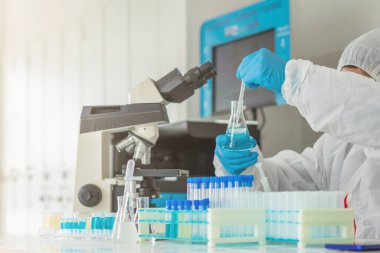 Ekip doktorları COVID-19 koronavirüsünü incelemek ve salgını durdurmak için koronavirüs aşısını araştırmak için koronavirüs koruyucu giysi ve lastik eldiven giyerler..