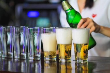 Yumuşak Işık ve Yumuşak Odaklanma, genç kadın başarıyı kutlayan müşterilere servis yapmak için bardakların üzerine bira doldurdu. Rahatlamak için alkol ya da bira içme fikri.