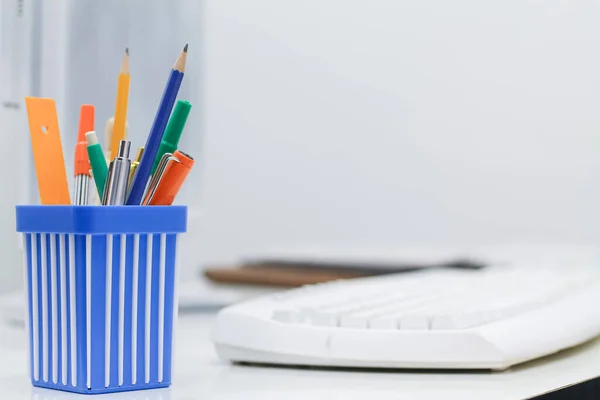 A white desk with writing utensils such as pens and pencils is placed on the desk in the house. A desk set up at home to reduce travel risks during the coronavirus outbreak.