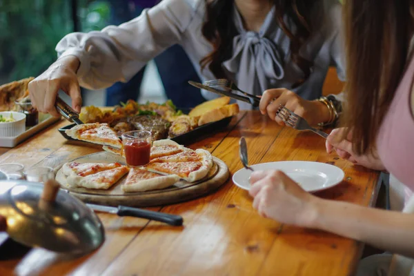 A young woman is happy to see the food on the table and choose the pizza menu to eat with good taste. Pizza menus are perfect for banquets among friends and family as they are comfortable to eat