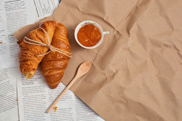 Croissant en un fondo de los periódicos con mermelada — Foto de Stock