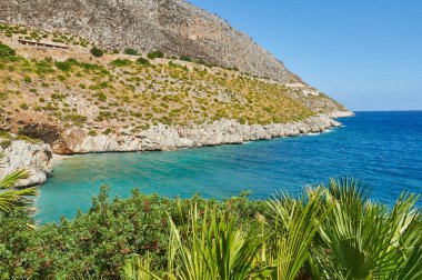 İtalya 'daki cennet plajı: mükemmel şeffaf turkuaz su, yeşil taşlarla çevrili beyaz çakıllar. 