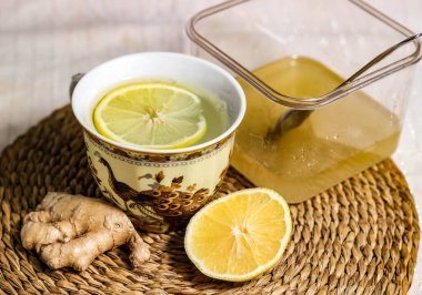 Limon ve ballı sıcak içecek. Yanında zencefil ve limon var. Grip ve soğuk algınlığı önleme ve tedavi kavramı. Kapat..