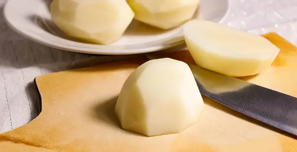 Rauwe Geschilde Aardappelen Een Bord Snijplank Horizontaal Frame Natuurlijk Licht — Stockfoto