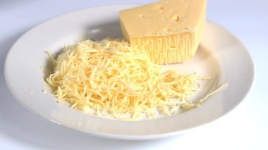 Bir parça sert peynir ve hafif tabakta rendelenmiş peynir. Yakın plan..