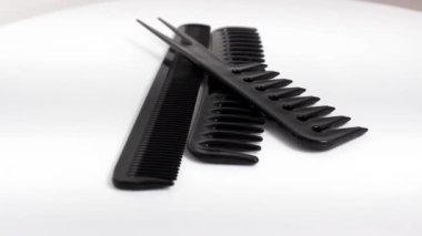 Beyaz arka planda birkaç farklı siyah tarak. Döner masa. Seçici atış.